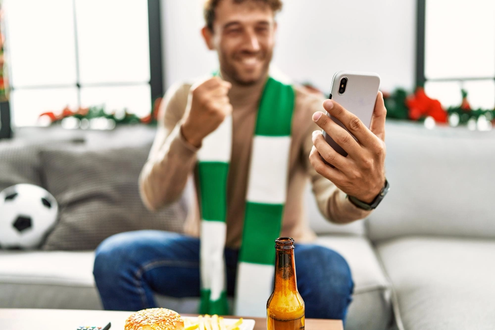 Football fan with phone and beer
